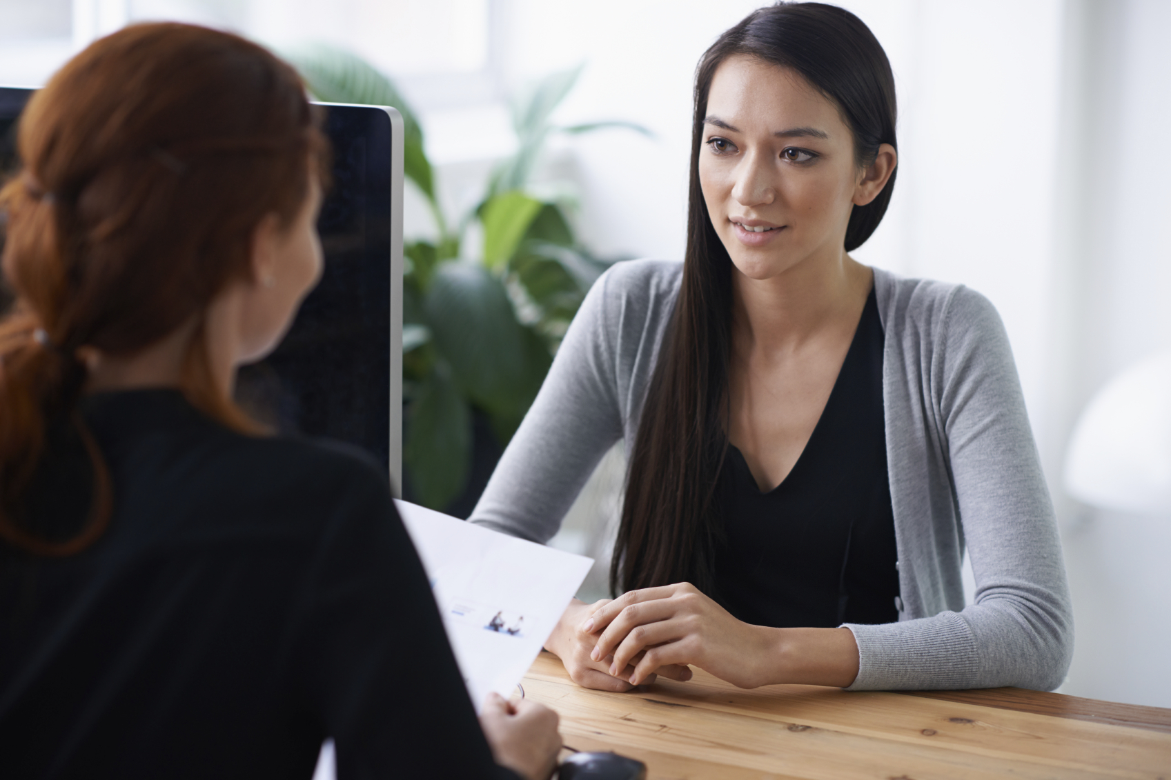 Young woman during a job interview. Recruiter with back to viewer